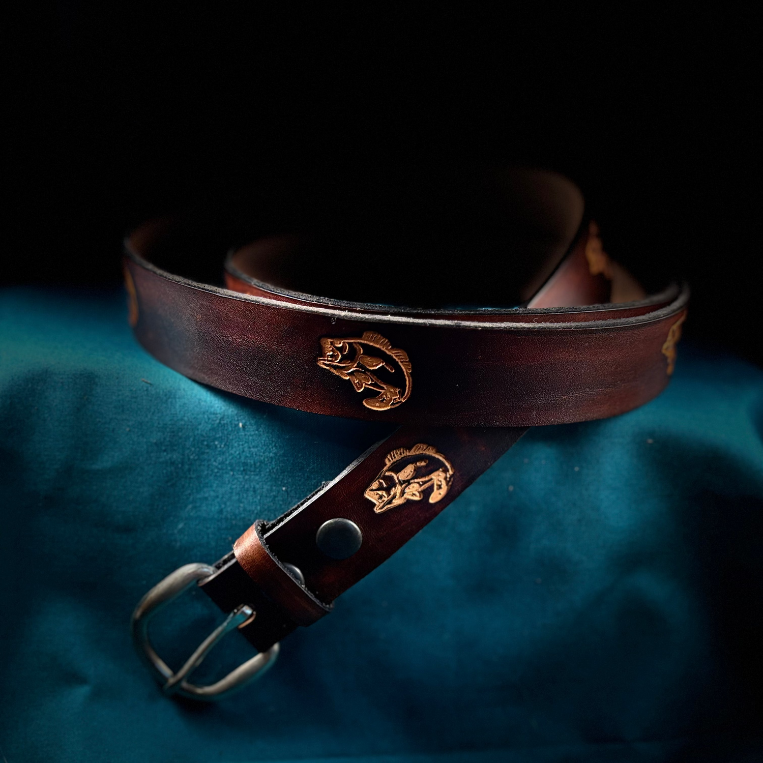 Brown leather belt with gold emblem on a blue fabric background
