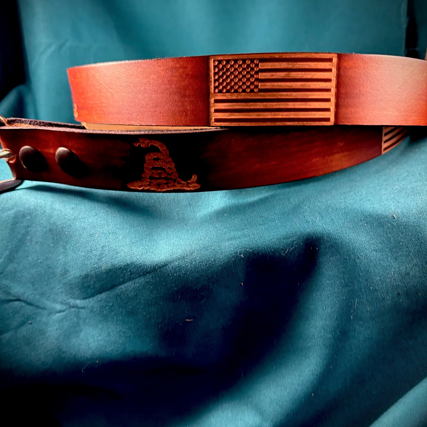 Brown leather belt with American flag design on a blue fabric background