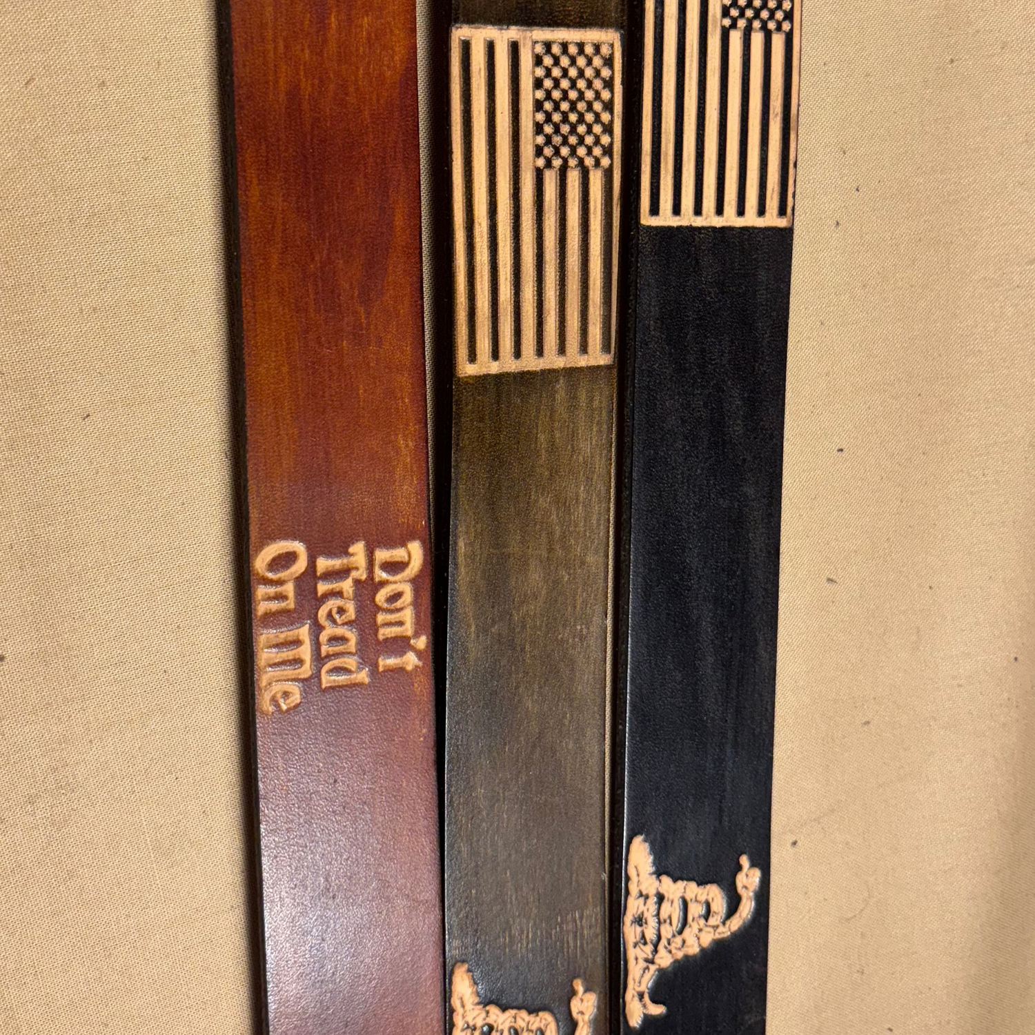 Three wooden sticks with engraved designs on a beige background