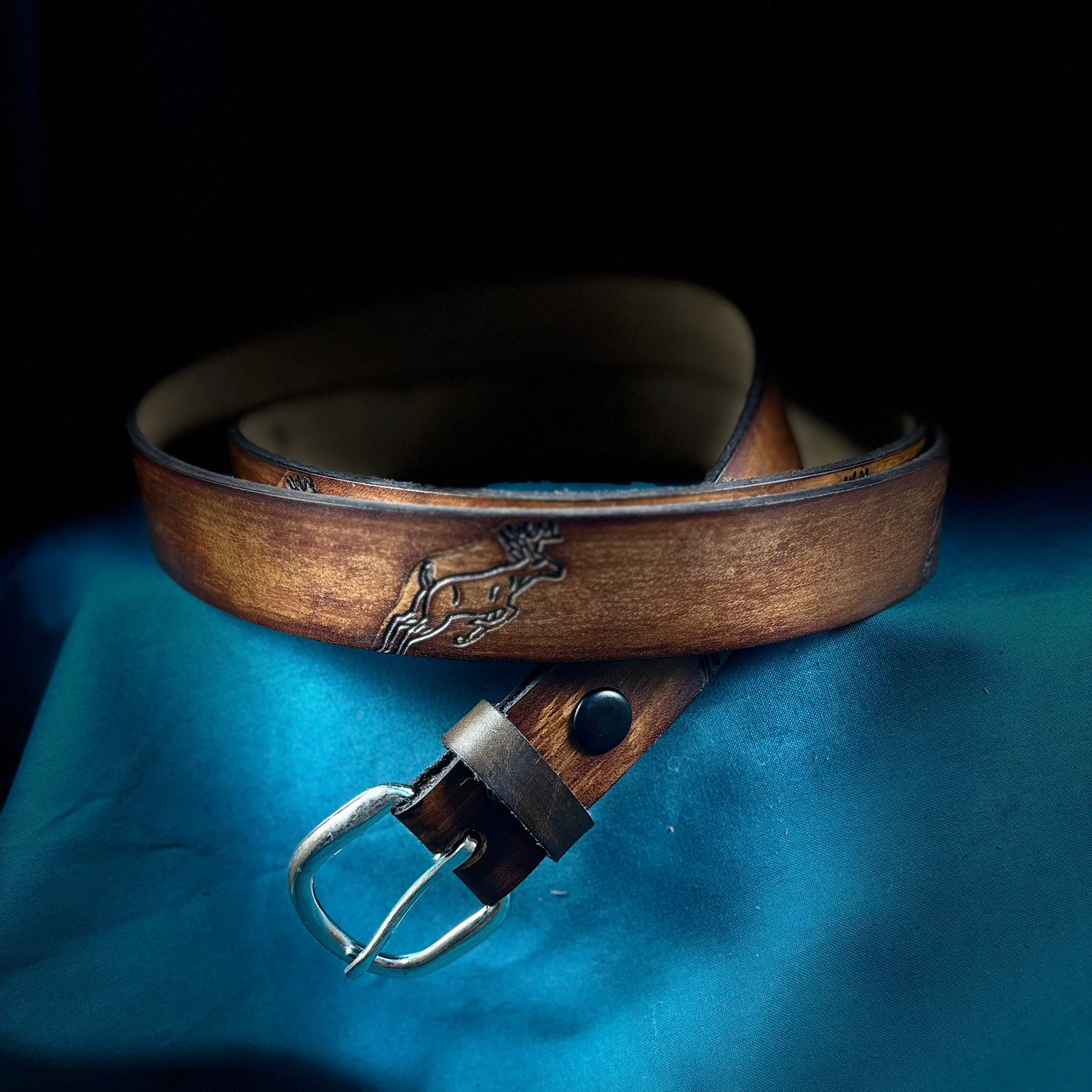 Brown leather belt with a buckle on a blue fabric background