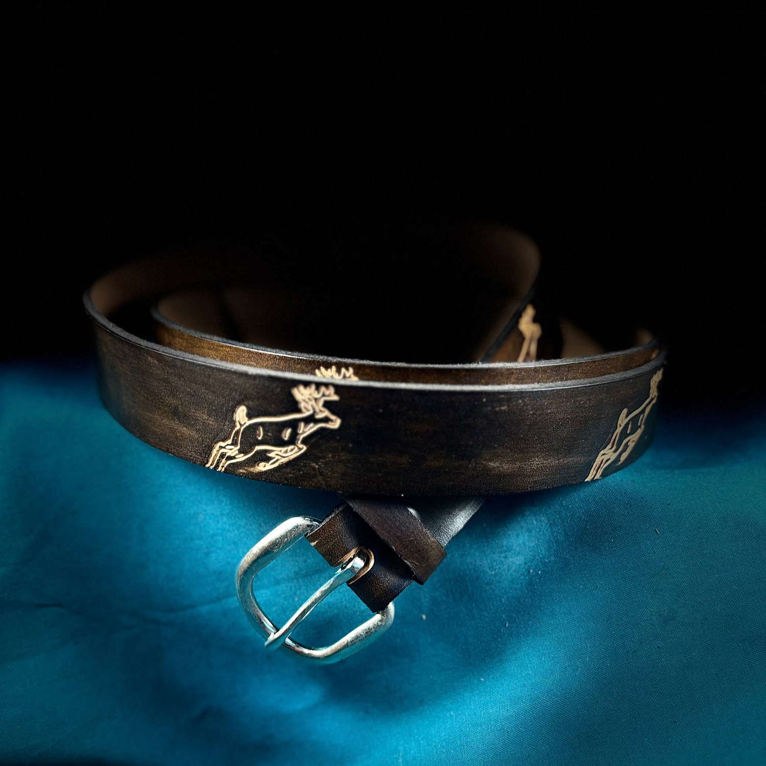 Brown leather belt with gold embossed design on a blue fabric background
