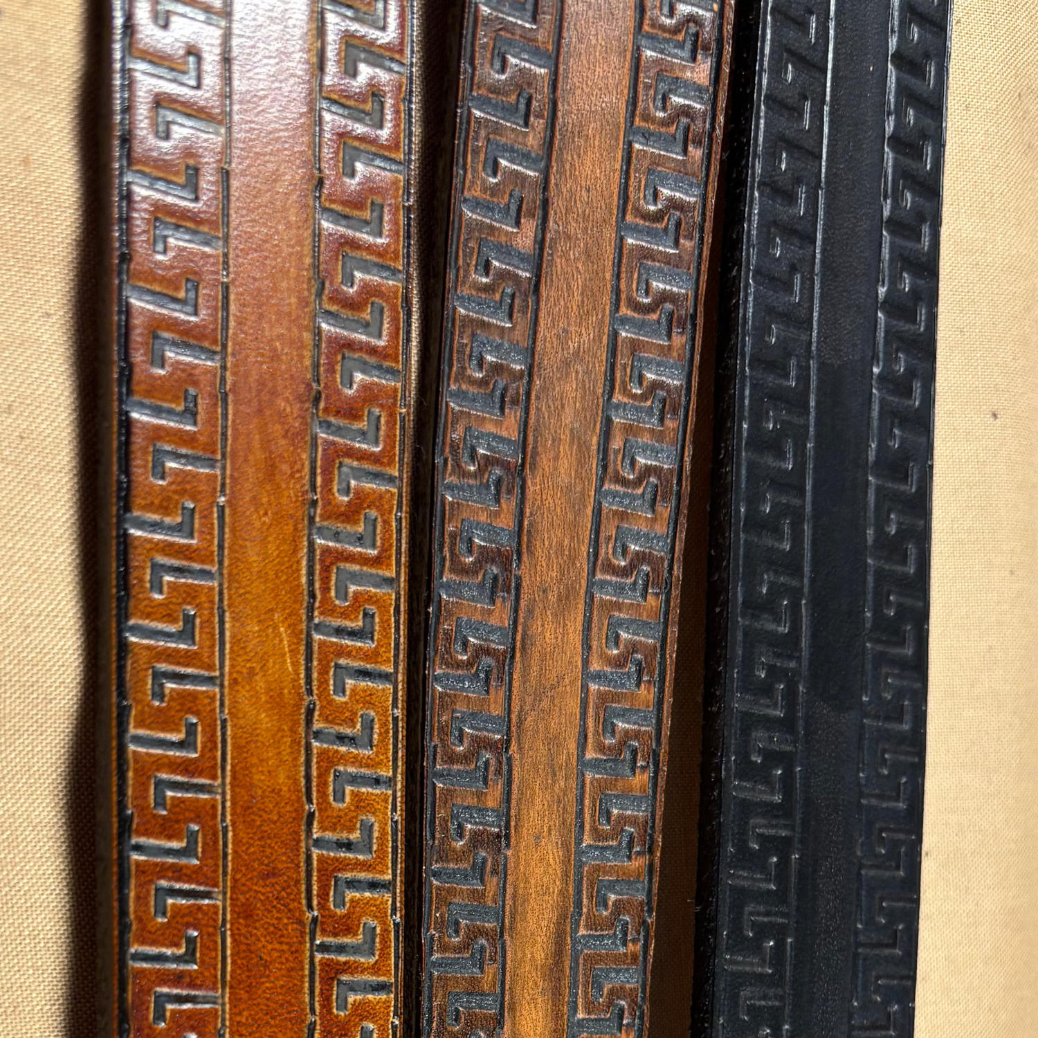 Three wooden picture frames with decorative patterns on a beige background