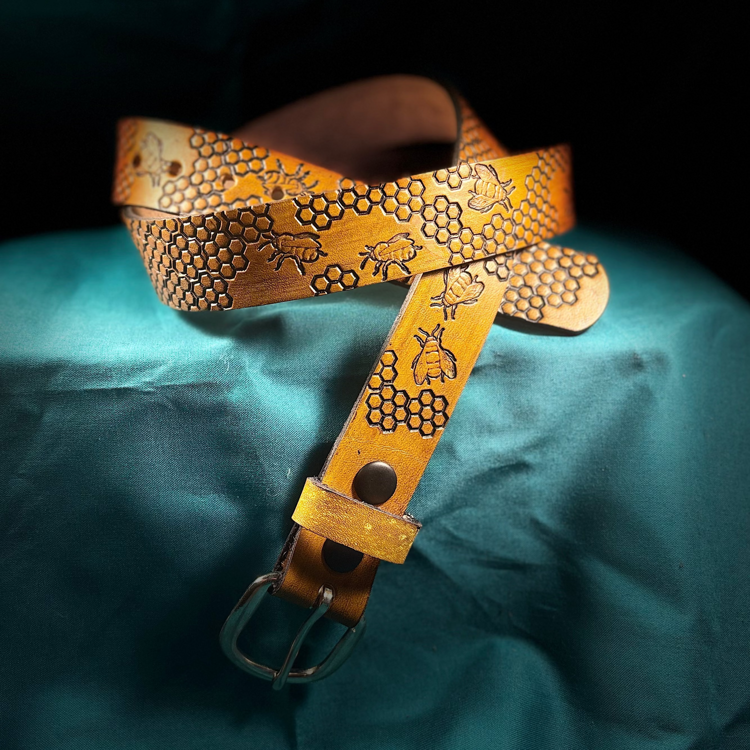 Decorative leather belt with honeycomb pattern on a teal fabric background