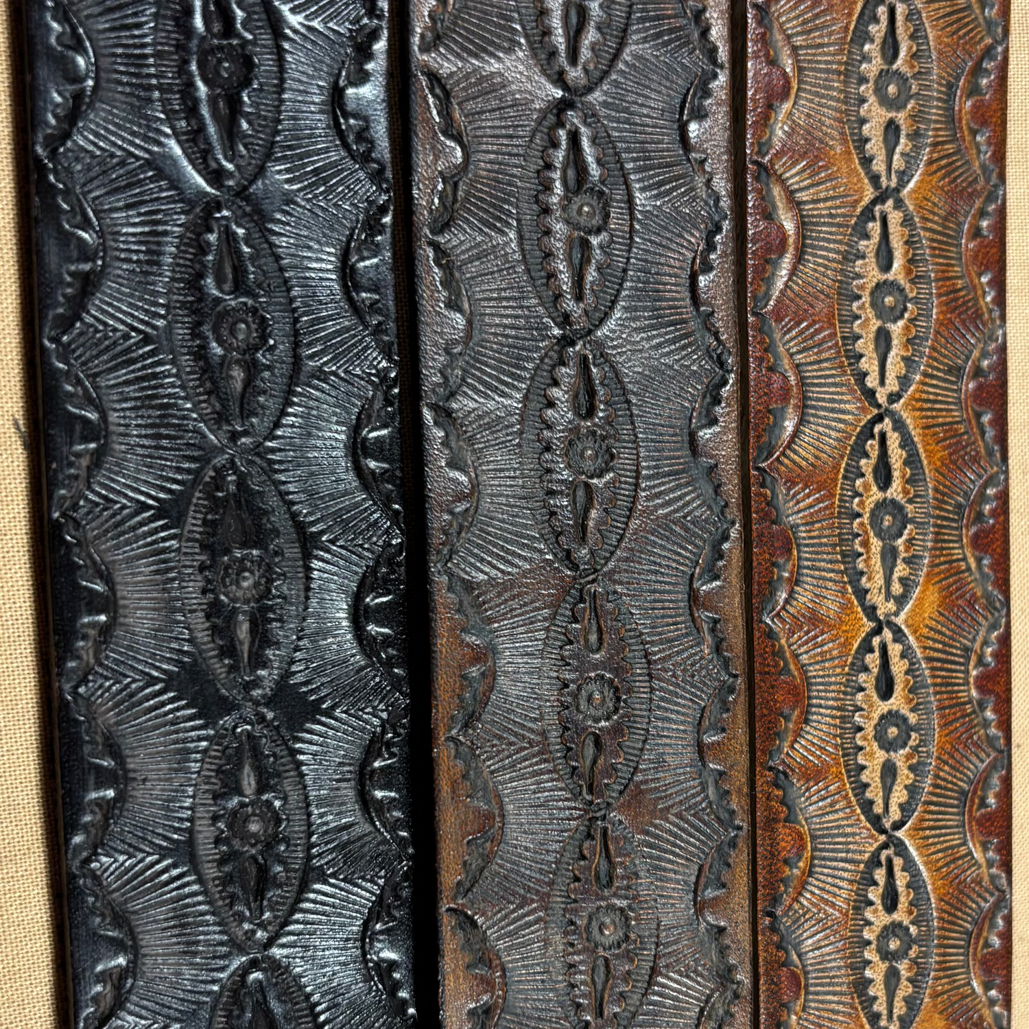 Three leather straps with embossed patterns on a beige background