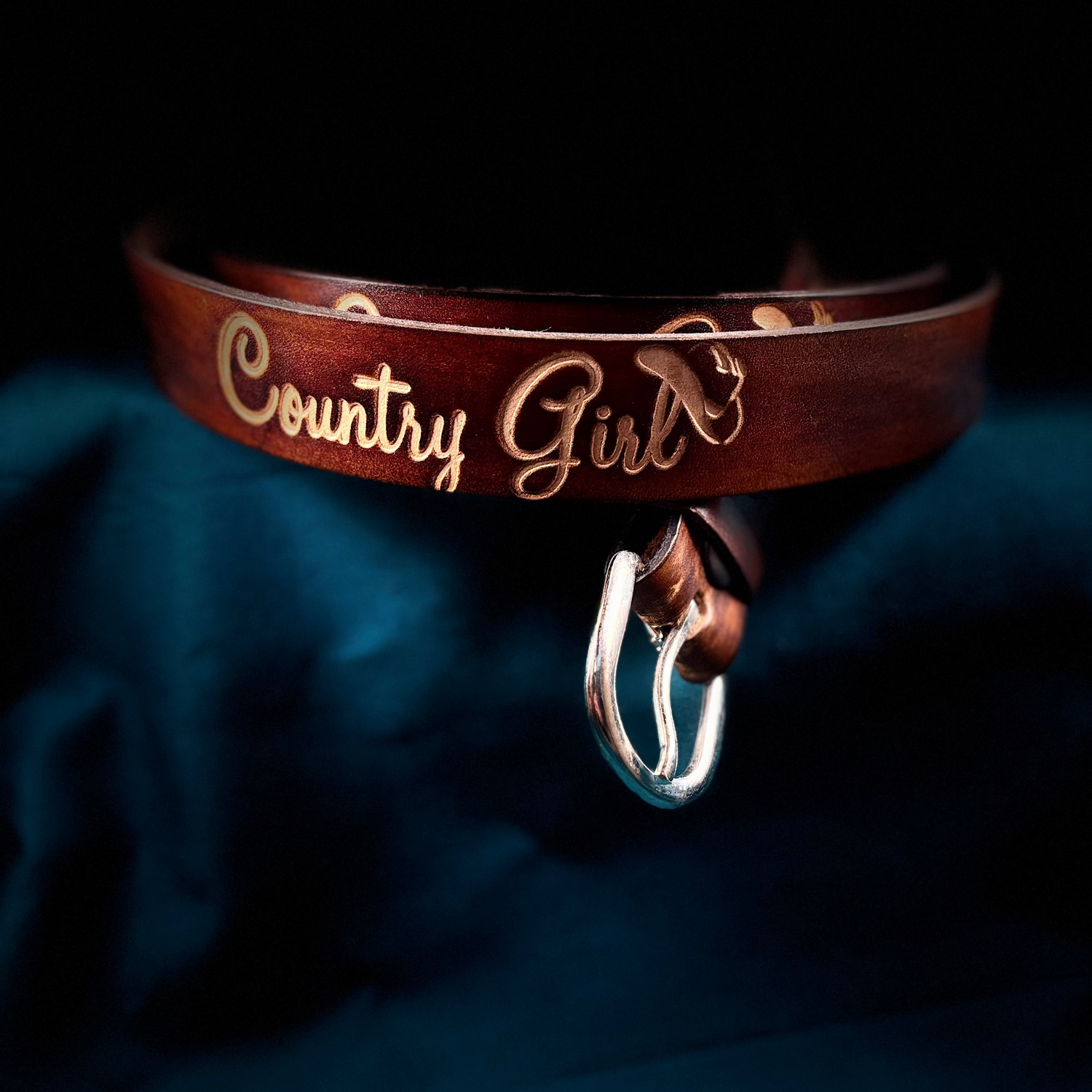 Brown leather belt with 'Country Girl' engraving and silver buckle on a dark background