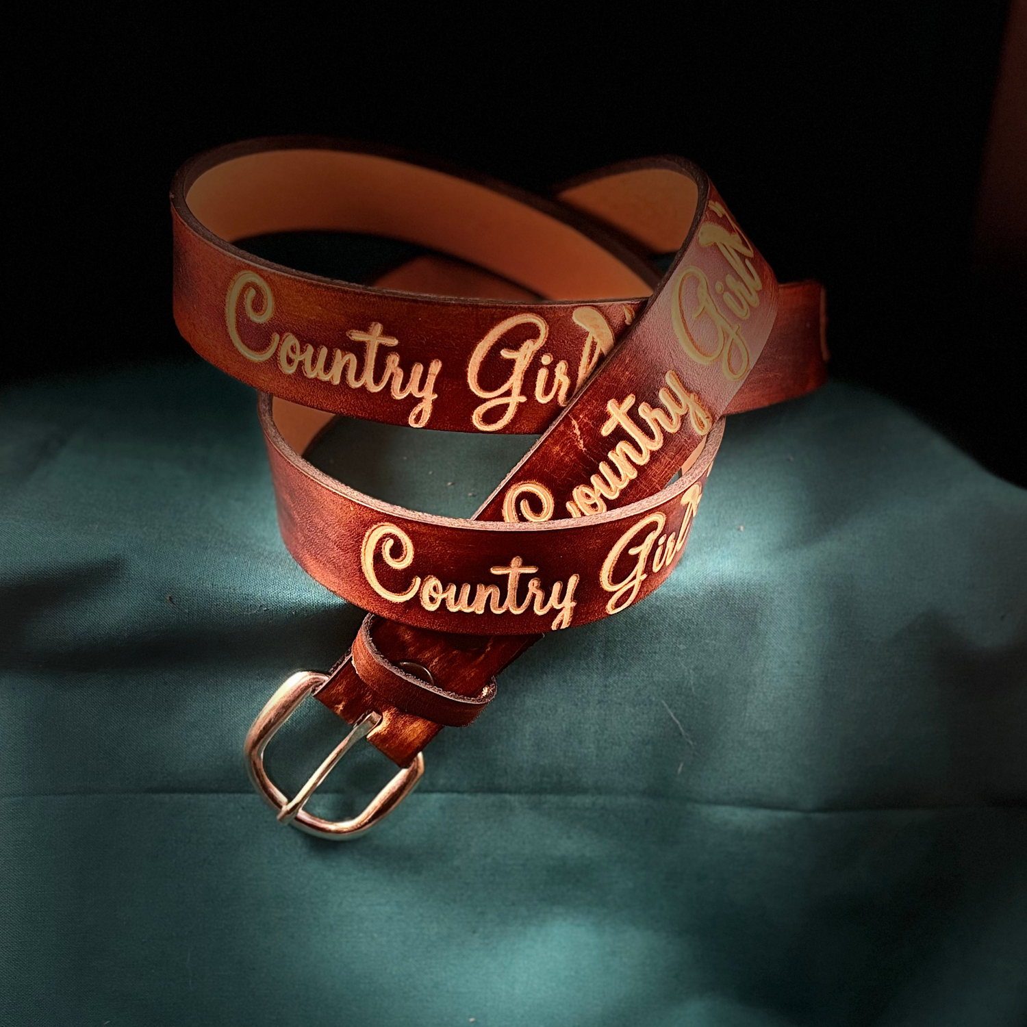 Brown belt with 'Country Girl' text on a green surface