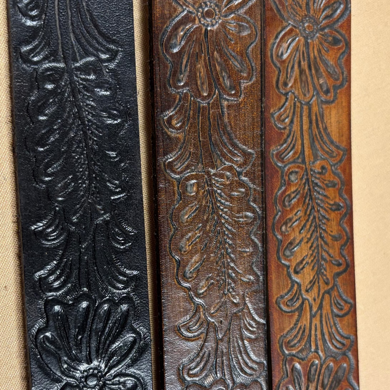 Three leather straps with floral embossing on a beige background