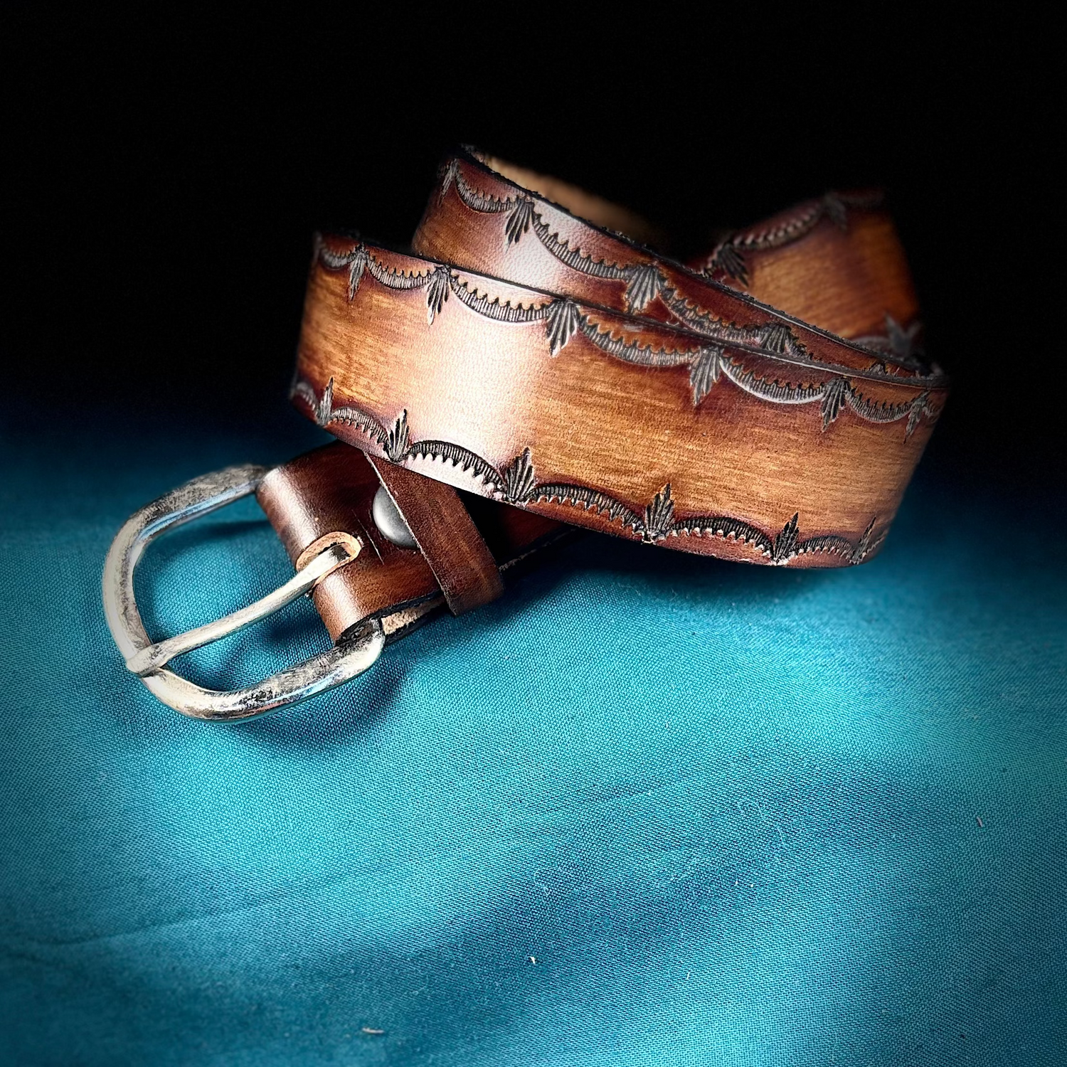 Brown leather belt with decorative buckle on a blue fabric background