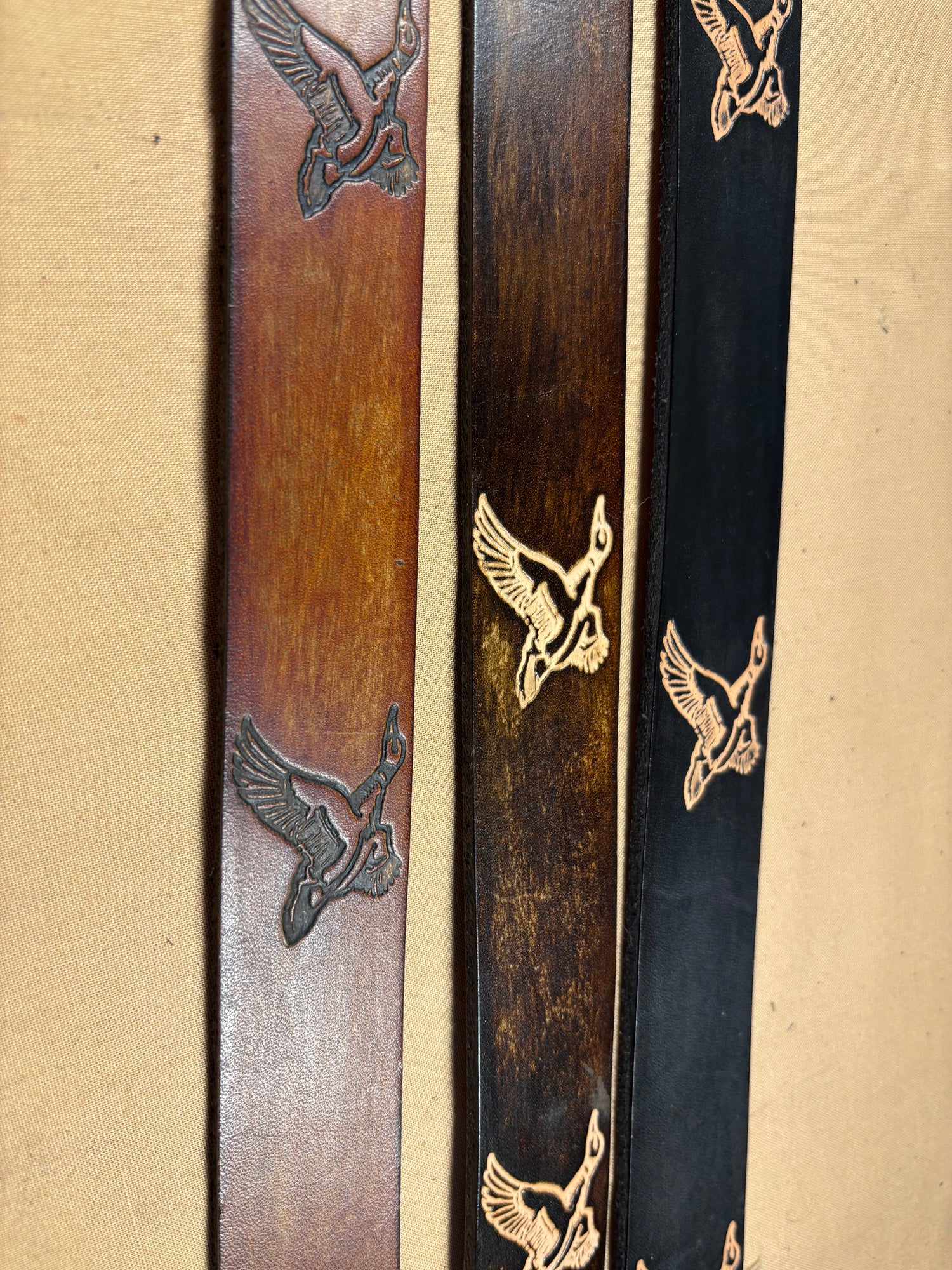 Three wooden sticks with engraved bird designs on a beige background