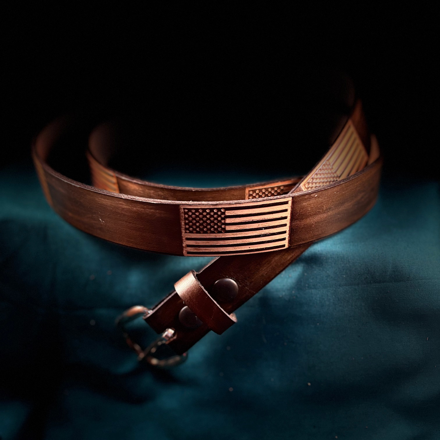 Brown leather belt with American flag buckle on a dark background