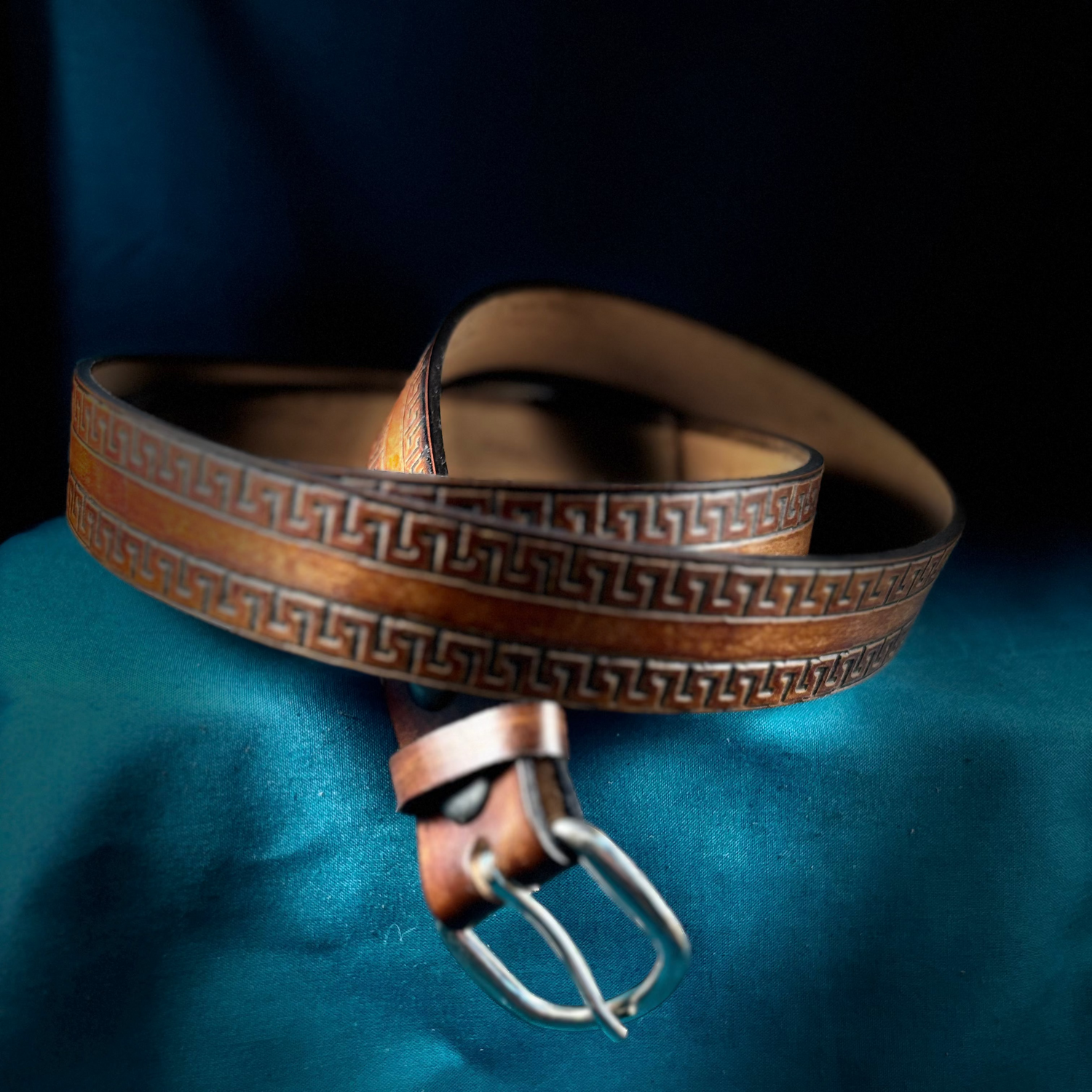 Brown leather belt with intricate design on a blue background