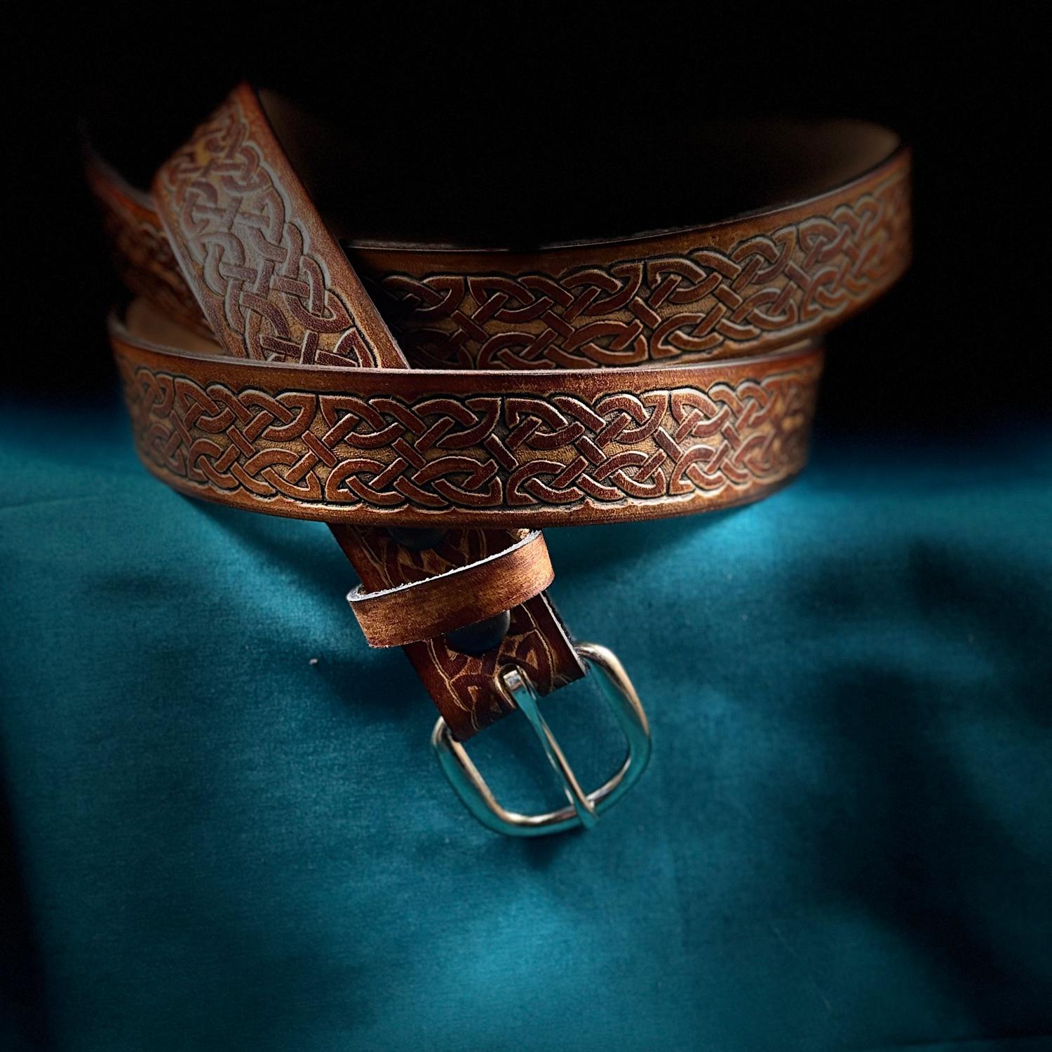 Brown leather belt with intricate designs on a blue fabric background