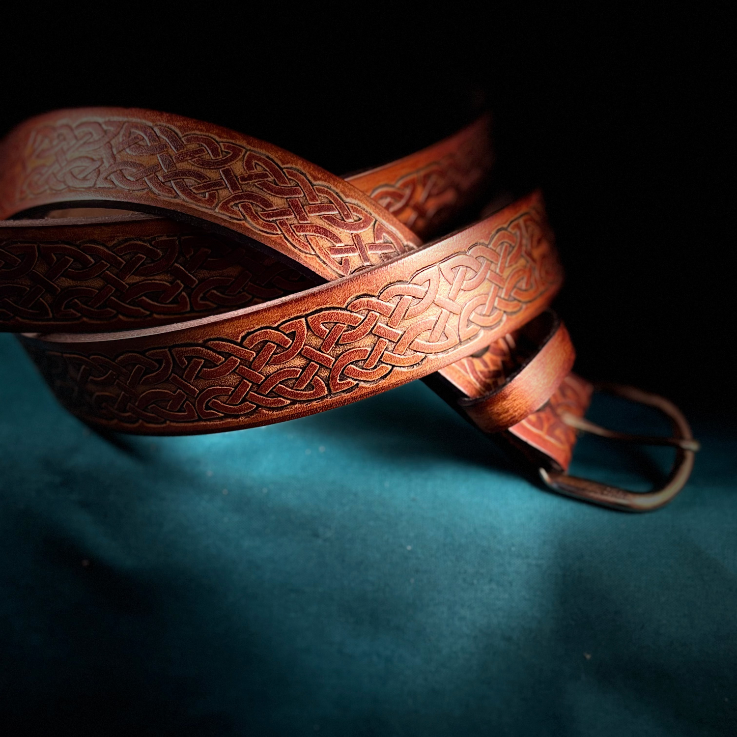 Brown leather belt with intricate patterns on a dark background