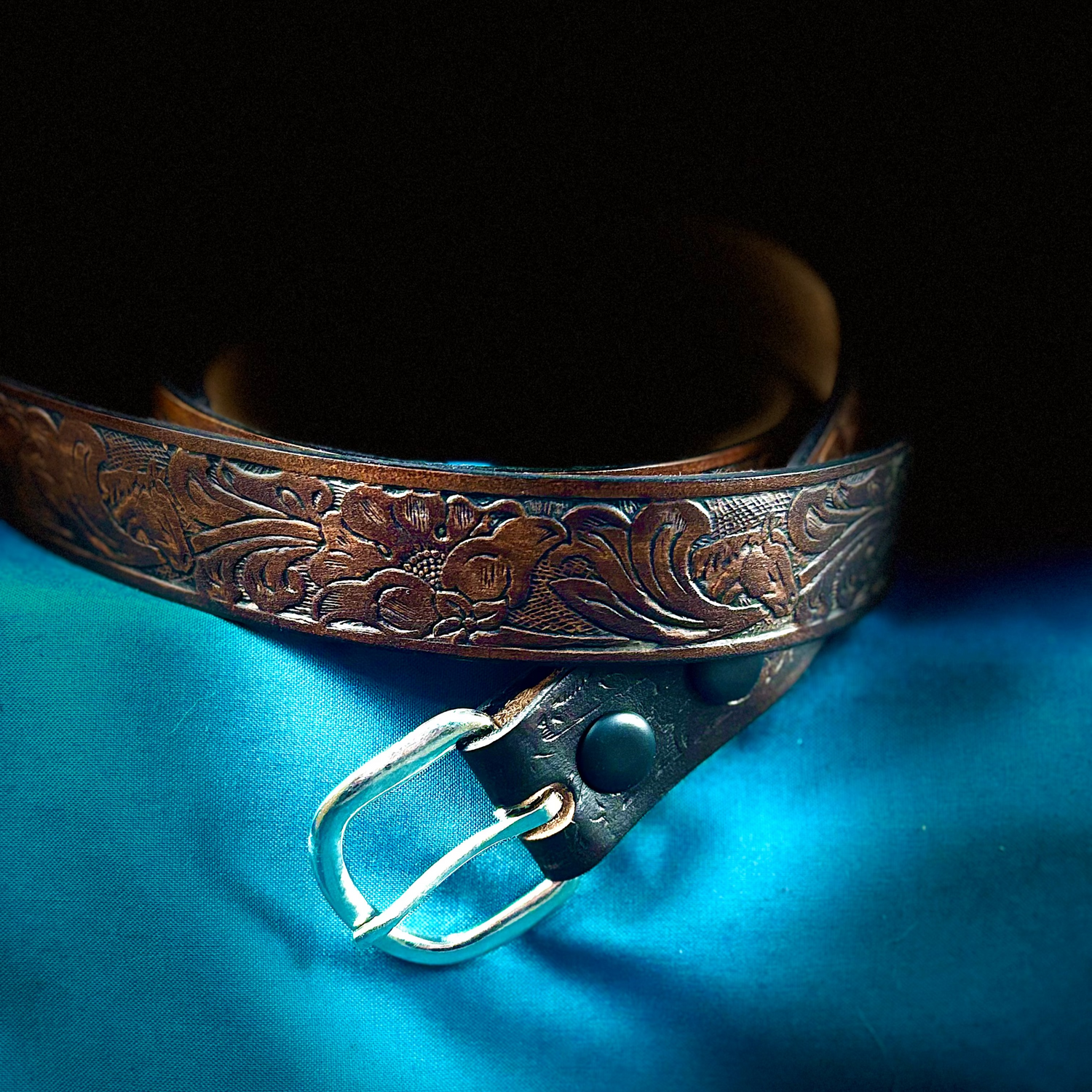 Decorative leather belt with floral patterns on a blue fabric background