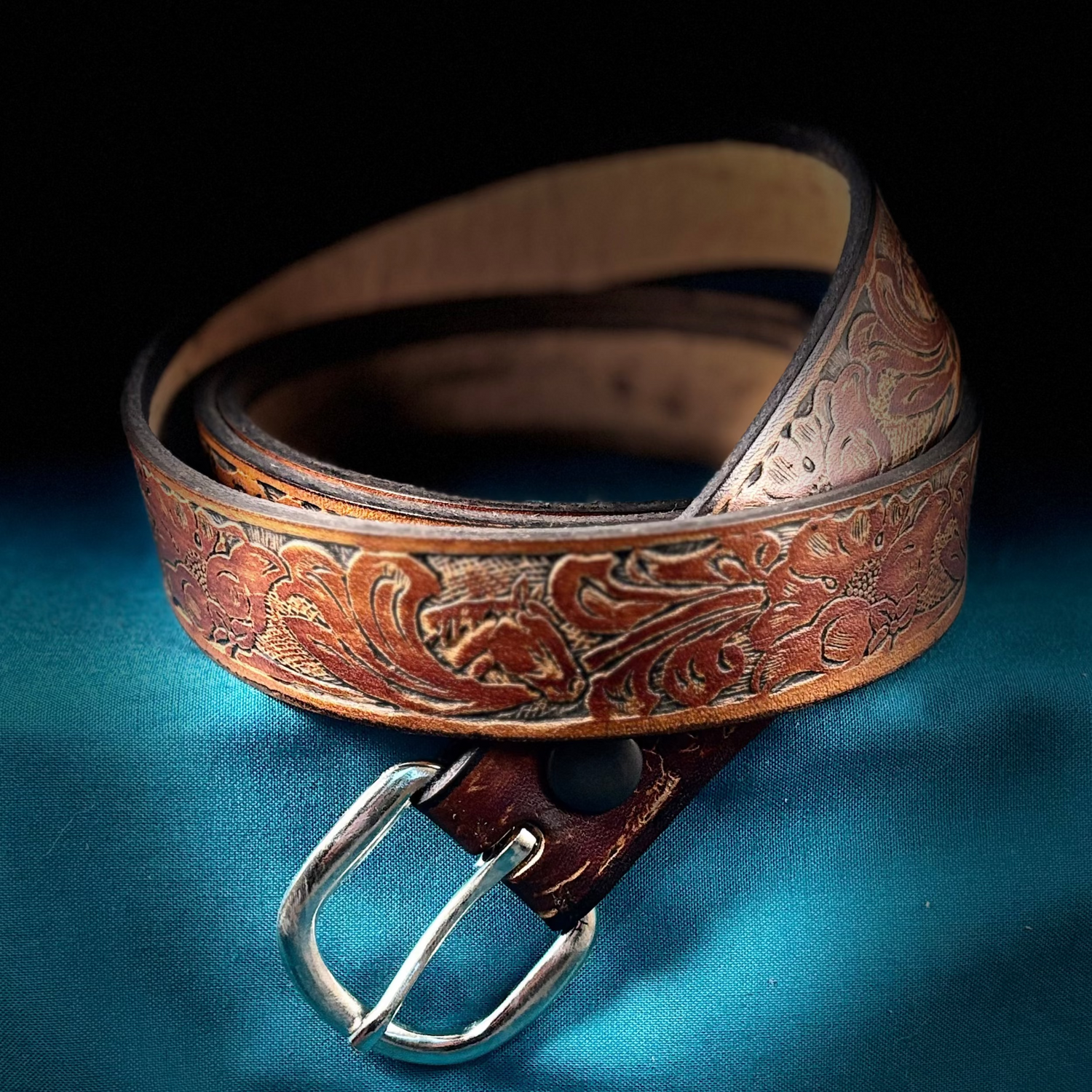 Brown leather belt with intricate designs on a blue fabric background